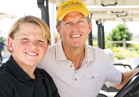 a father and son smiling in a golf cart